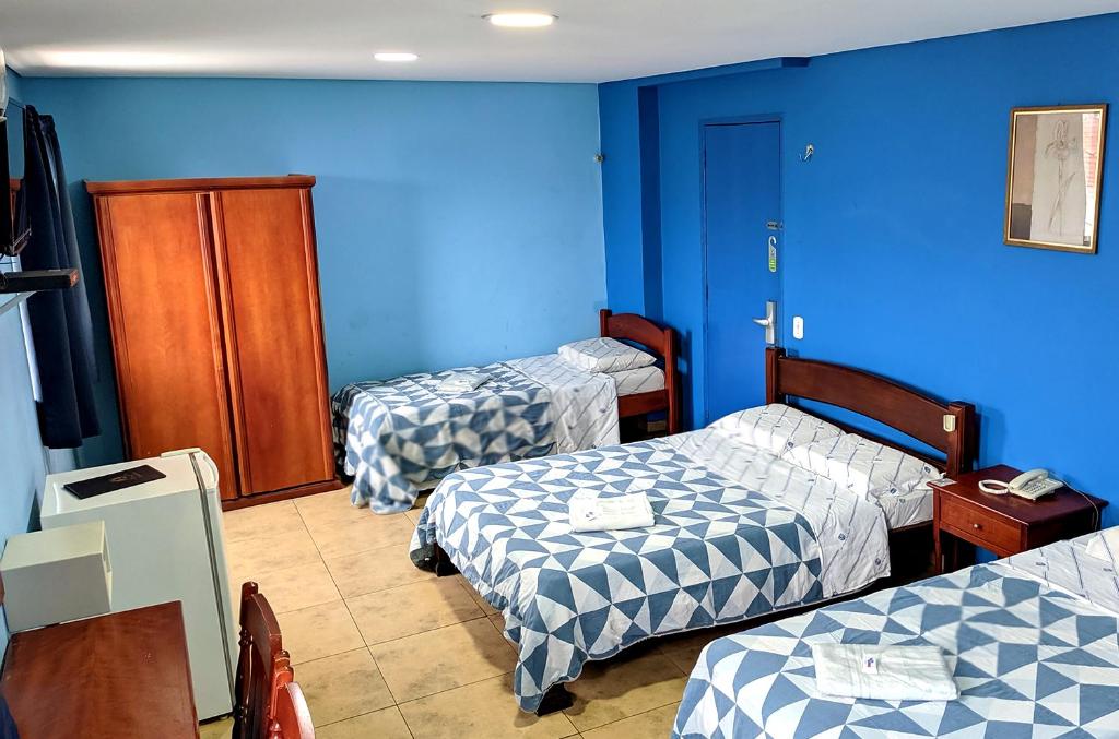 three beds in a room with blue walls at LM Hotel in Sao Paulo