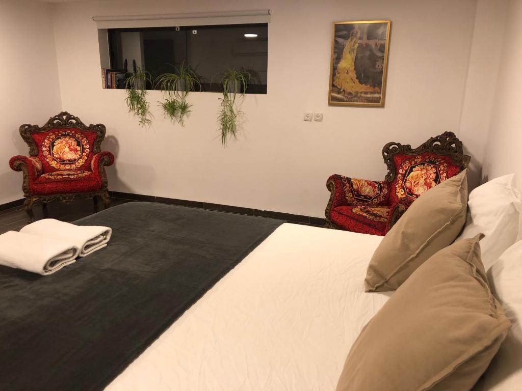 a bedroom with a large bed with two chairs at Hassan Guesthouse in Nazareth