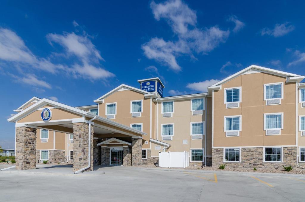 a hotel with a building with a parking lot at Cobblestone Hotel & Suites - Urbana in Urbana