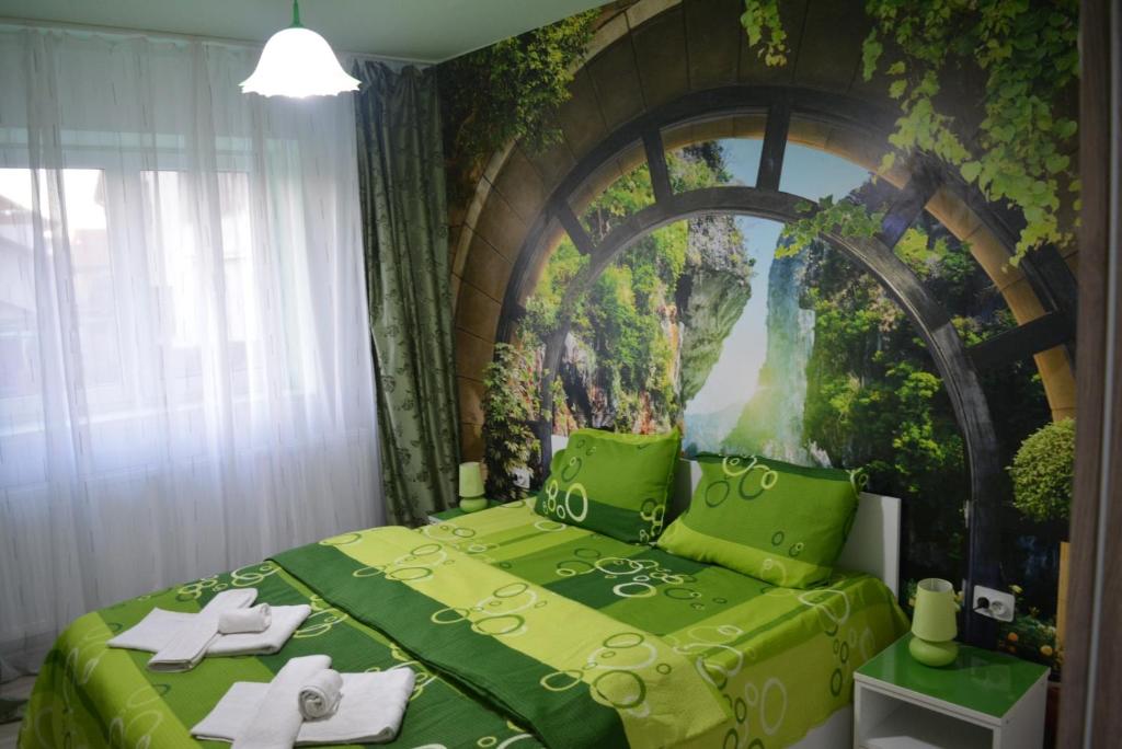 Un dormitorio con una cama verde con una pintura en la pared en Green rooms Hunedoara, en Hunedoara
