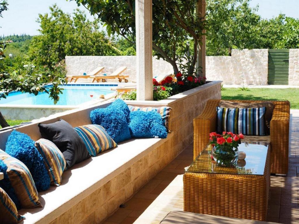 a patio with pillows on a bench next to a pool at Villa Antonija in Čilipi