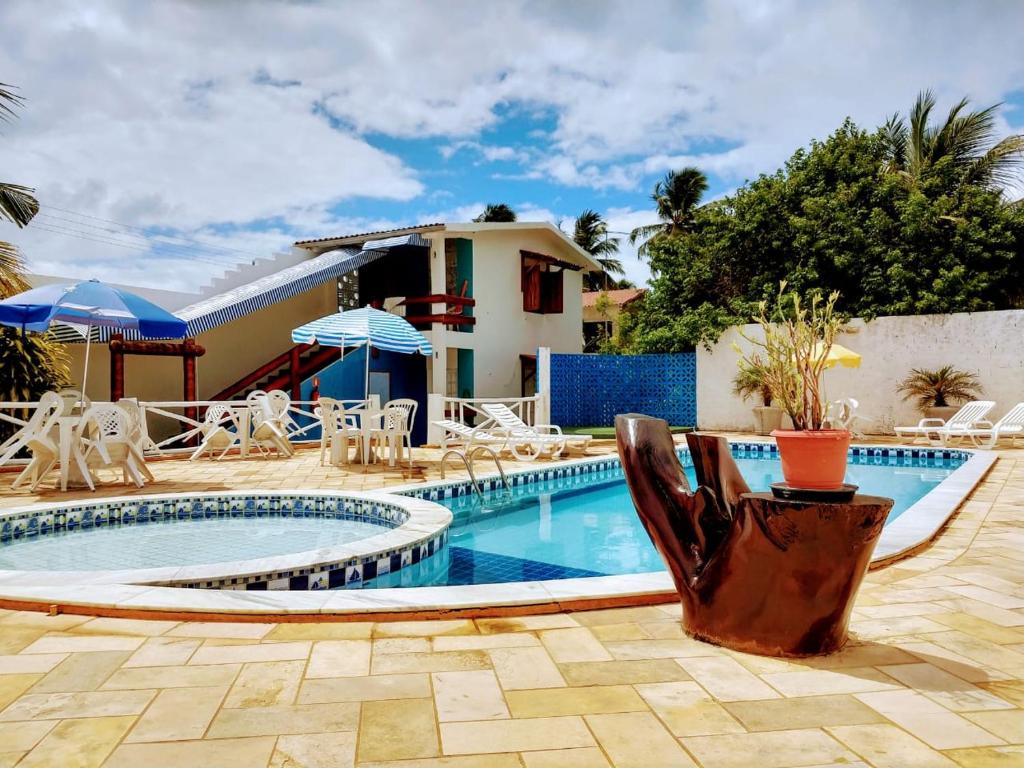 a swimming pool with chairs and a house at Pousada Don Robledo in São Miguel dos Milagres
