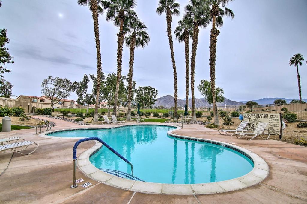 uma piscina com palmeiras e espreguiçadeiras em Palm Royale CC Apt with Golf Course and Mtn Views! em La Quinta
