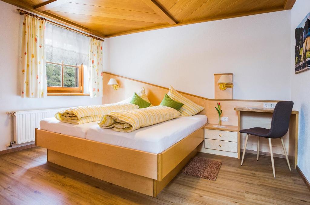 a bedroom with a bed with a desk and a chair at Gästehaus Fitsch in Obsteig