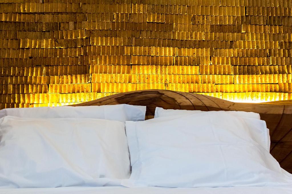 1 cama con almohadas blancas junto a una pared de madera en Feel at Home Guest House en Ovar