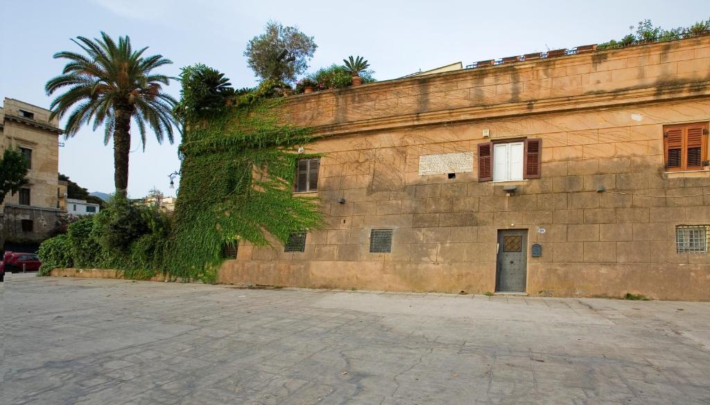 un viejo edificio de ladrillo con una palmera al lado en Cleopatra B&B, en Palermo