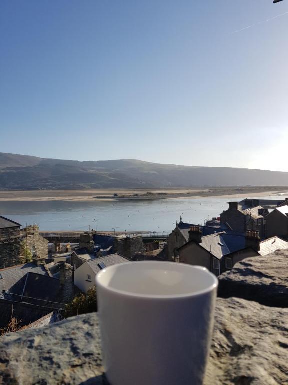 a cup sitting on a ledge with a view of a city at Penbryn Holidays, Barmouth in Barmouth