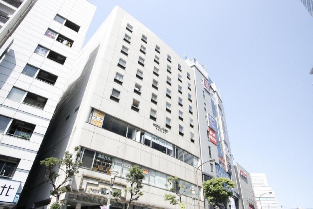 ein hohes weißes Gebäude mit Bäumen davor in der Unterkunft Hotel Abest Meguro / Vacation STAY 71390 in Tokio