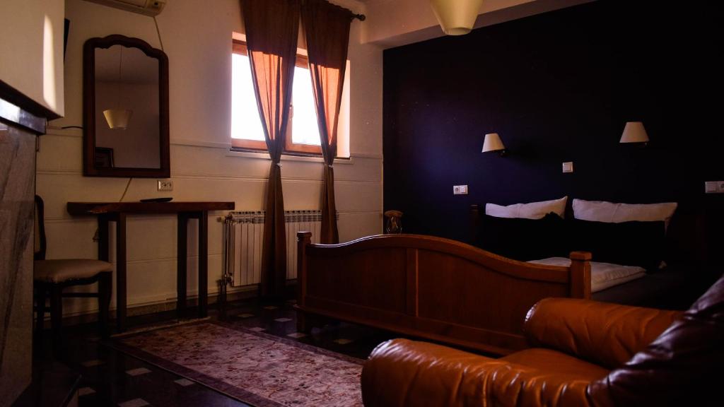 een woonkamer met een bed, een bank en een spiegel bij Hostel Mornar in Velika Kladuša