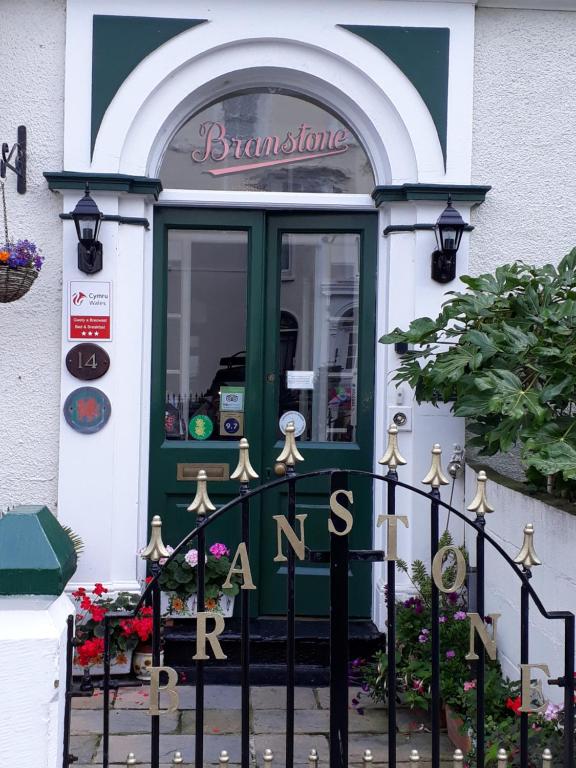 een voordeur van een winkel met een groene deur bij Branstone Guest House in Llandudno