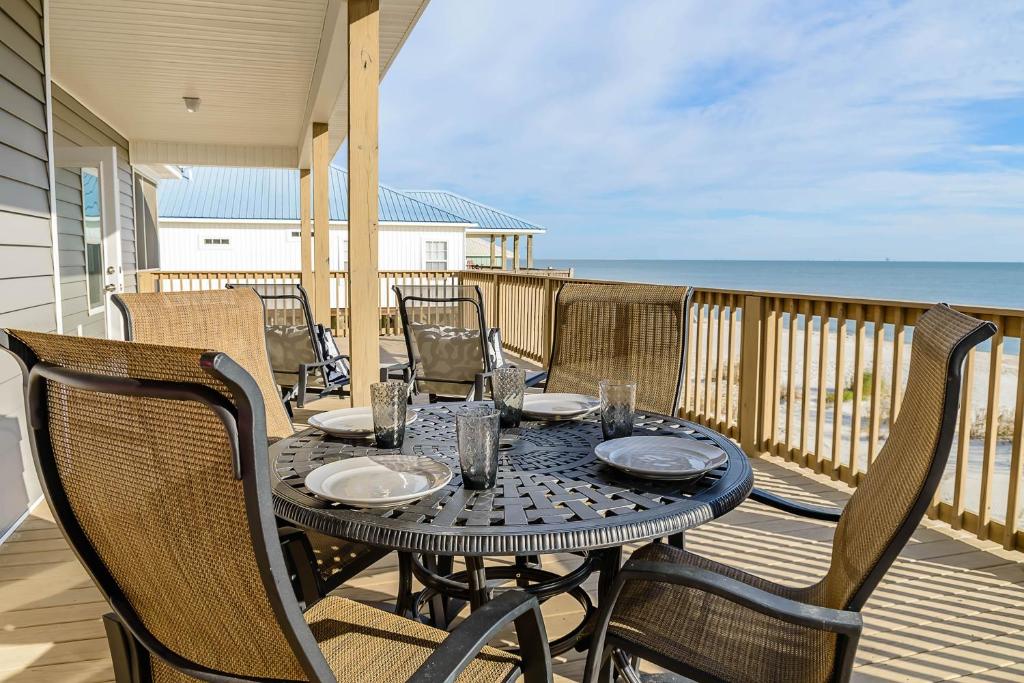 a table and chairs on a balcony with the ocean at Sassy Seagull in Dauphin Island