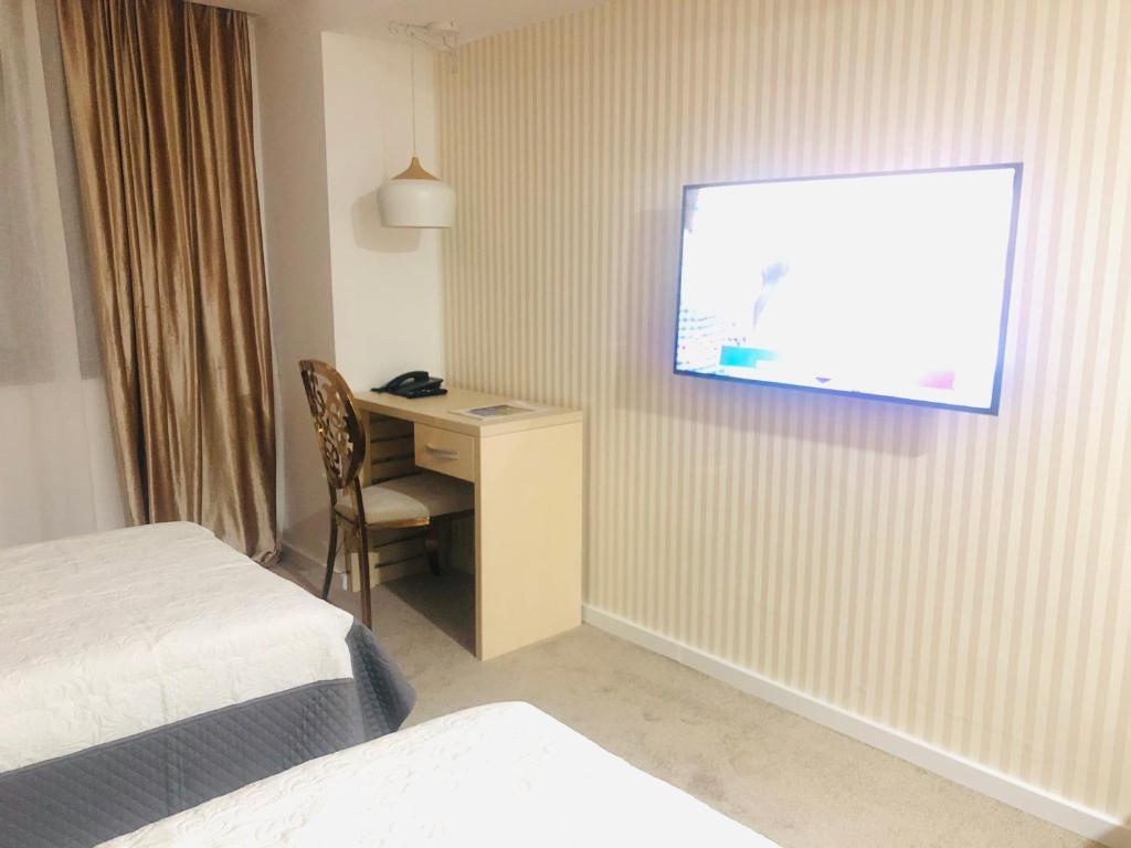 a hotel room with a desk and a television on the wall at Hotel Plaza in Craiova
