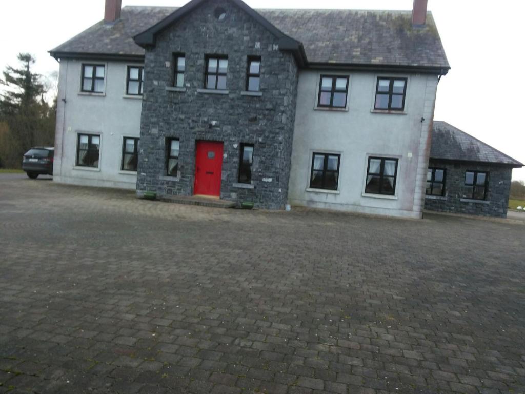 a large white house with a red door at Riverview Country House in Ballinasloe
