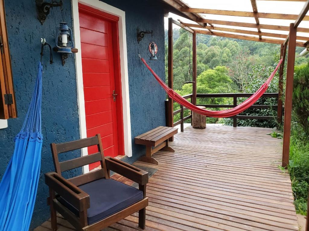 een veranda met een hangmat en een rode deur bij Vosso Lar com Vista Gramado in Gramado
