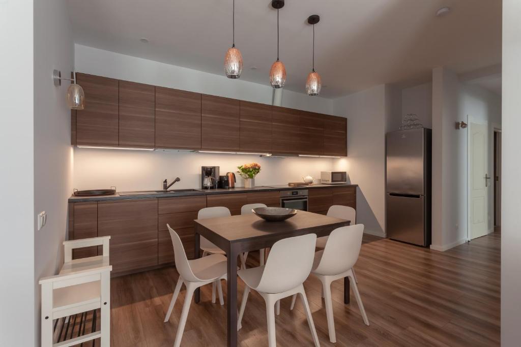 a kitchen with a wooden table and white chairs at Brand new flat heart of Vilnius in Vilnius