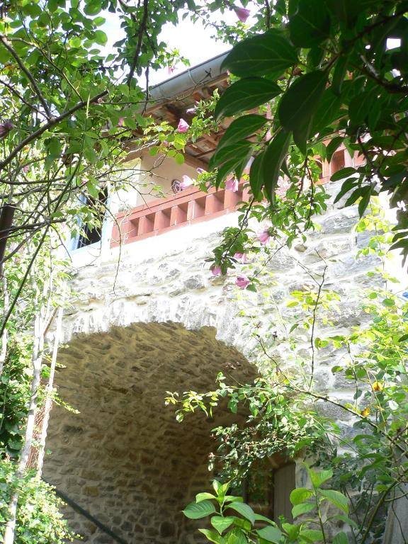 un mur en pierre avec un pont dans un jardin dans l'établissement Maison de village Ardéchoise à Les Vans, aux Vans