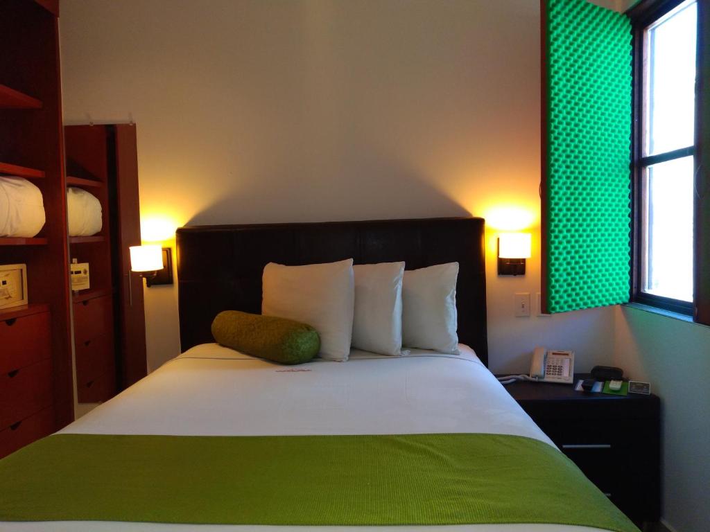 een slaapkamer met een groot bed met een groen hoofdeinde bij Suites La Concordia in Puebla