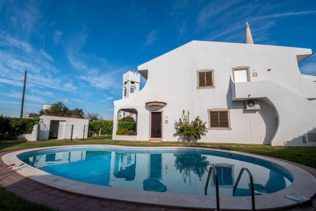 a house with a swimming pool in front of it at Apartamentos Pinto in Quarteira