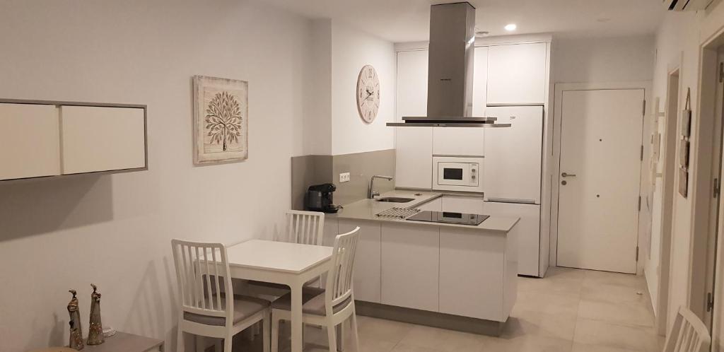 uma cozinha com armários brancos e uma mesa e cadeiras em Apartamento Iceberg Tarifa Parking gratuito em Tarifa
