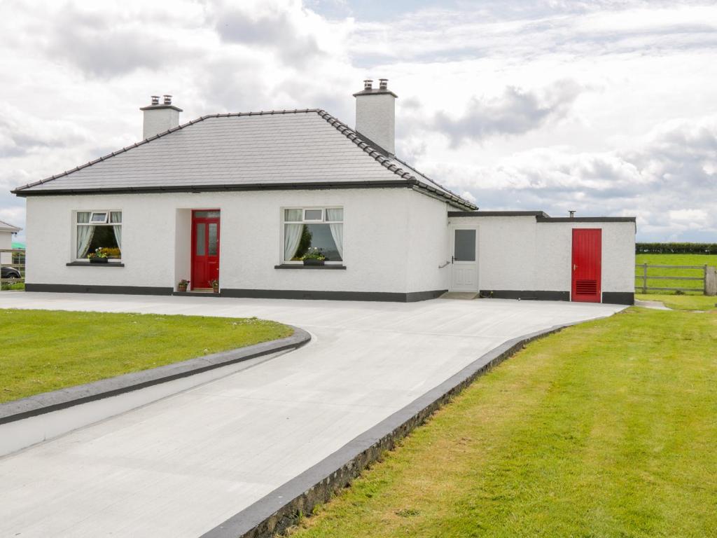 a white house with red doors and a driveway at Kate's Cottage in Ballina