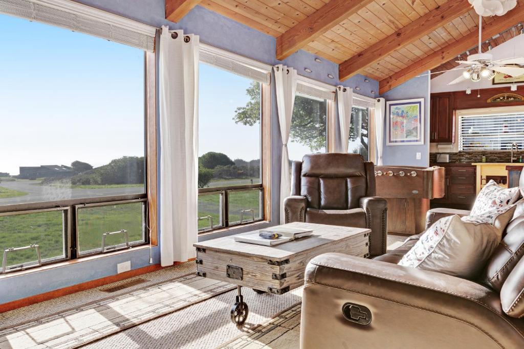 a living room with a couch and a table and windows at Ocean Star in Sea Ranch