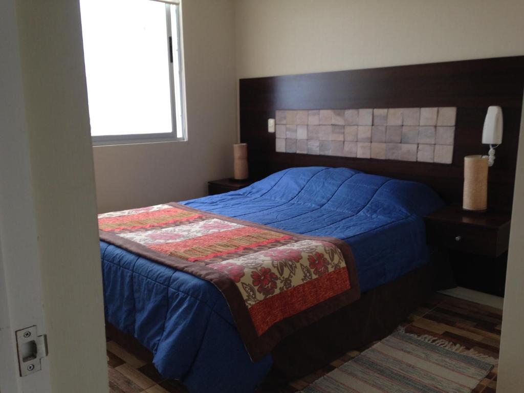 - une chambre avec un lit doté d'une couette bleue et d'une fenêtre dans l'établissement Departamento Av. del Mar de Coquimbo, à Coquimbo