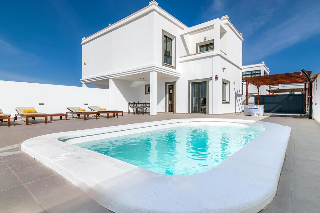 a villa with a swimming pool in front of a house at TEBAR BEACH in Yaiza