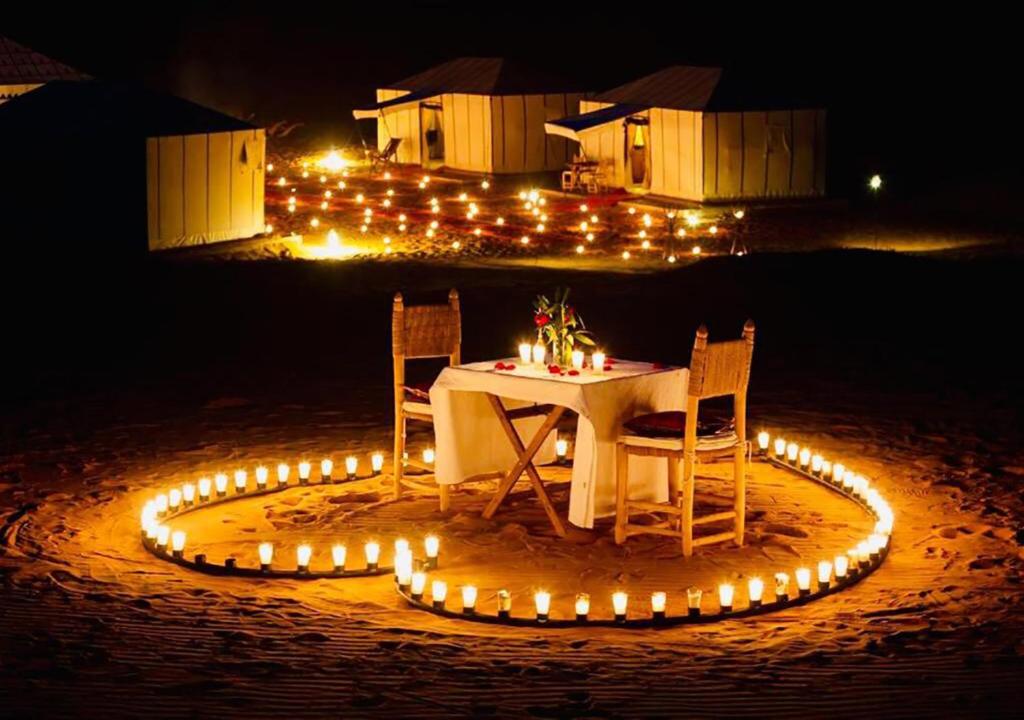 una mesa con sillas y luces en la playa en Mhamid Luxury Camp Experience en Mhamid