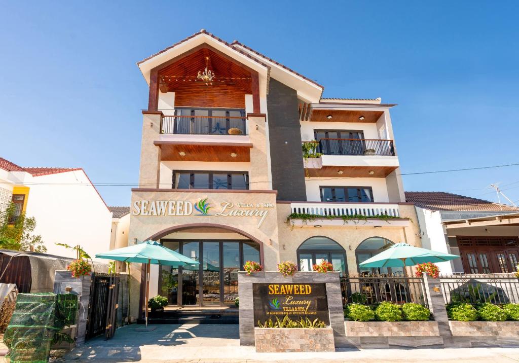 un grand bâtiment avec des parasols en face de celui-ci dans l'établissement Seaweed Luxury Villa & Spa, à Hội An