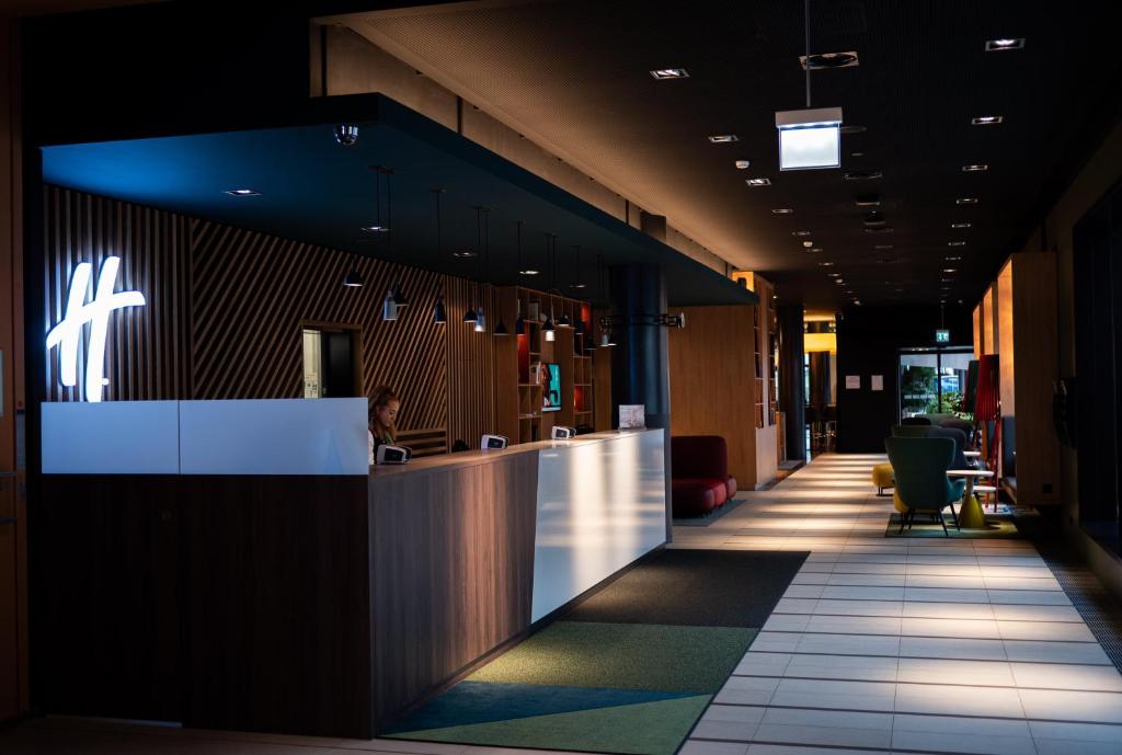 an office lobby with a reception counter and chairs at Holiday Inn Zürich Messe, an IHG Hotel in Zürich