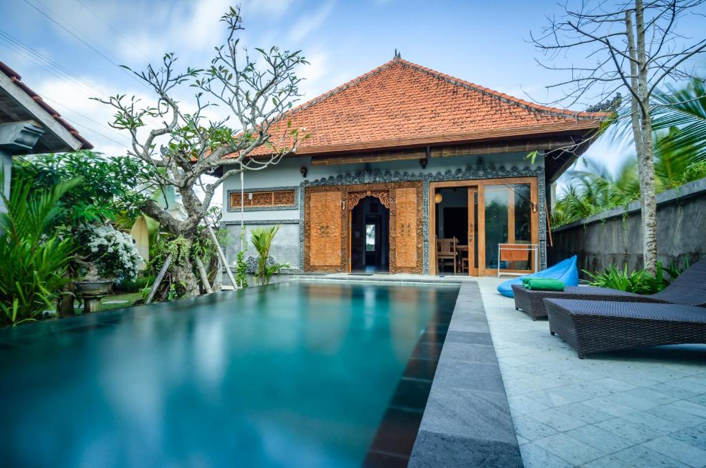 a swimming pool in front of a house at Fins Villa Medewi in Airsatang