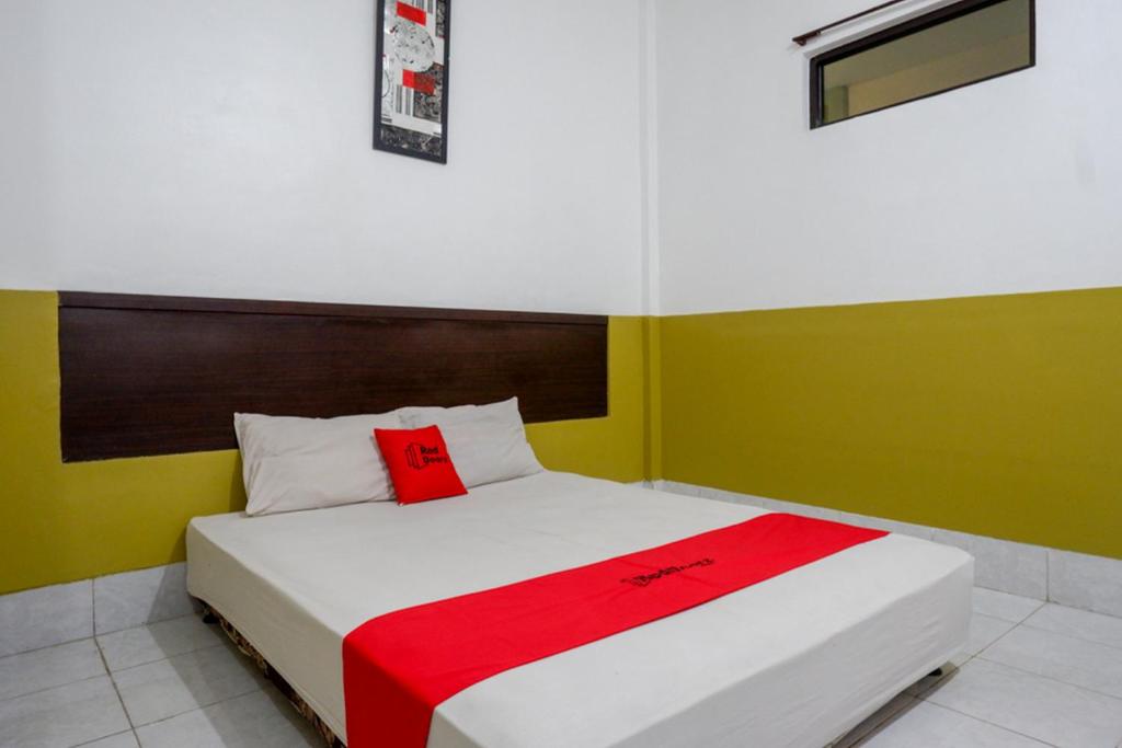 a bedroom with a bed with a red blanket on it at RedDoorz Syariah @ Hotel Wisma Indonesia Kendari in Kendari