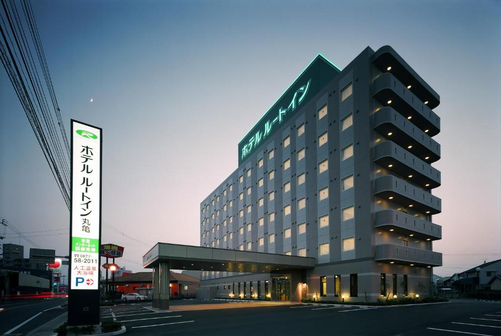 un gran edificio con un cartel delante en Hotel Route-Inn Marugame en Marugame