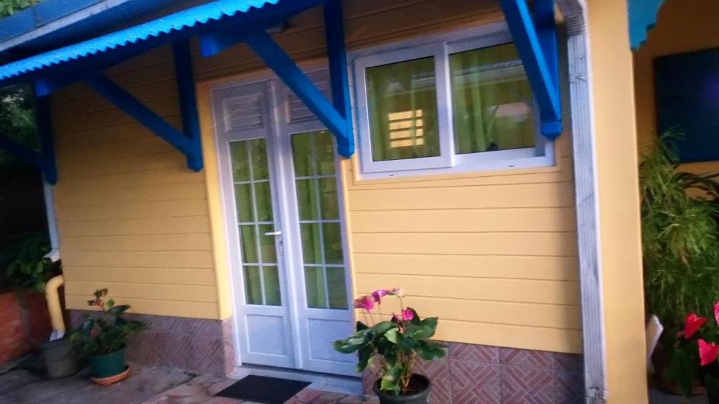 a house with yellow paint and blue trim at La cabane de Josephine in Le Lamentin