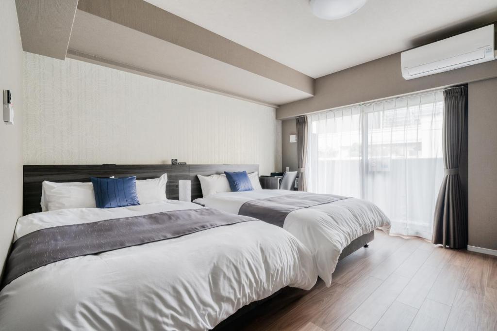 大阪市にあるBONコンドミニアム難波恵美須のベッド2台と窓が備わるホテルルームです。