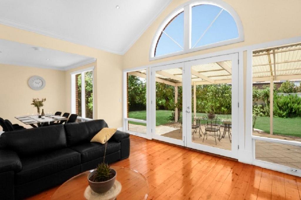 a living room with a black couch and a table at Adelaide Style Accommodation - City to Beach - Free WIFI - Free 3 car parking - Great location in Adelaide