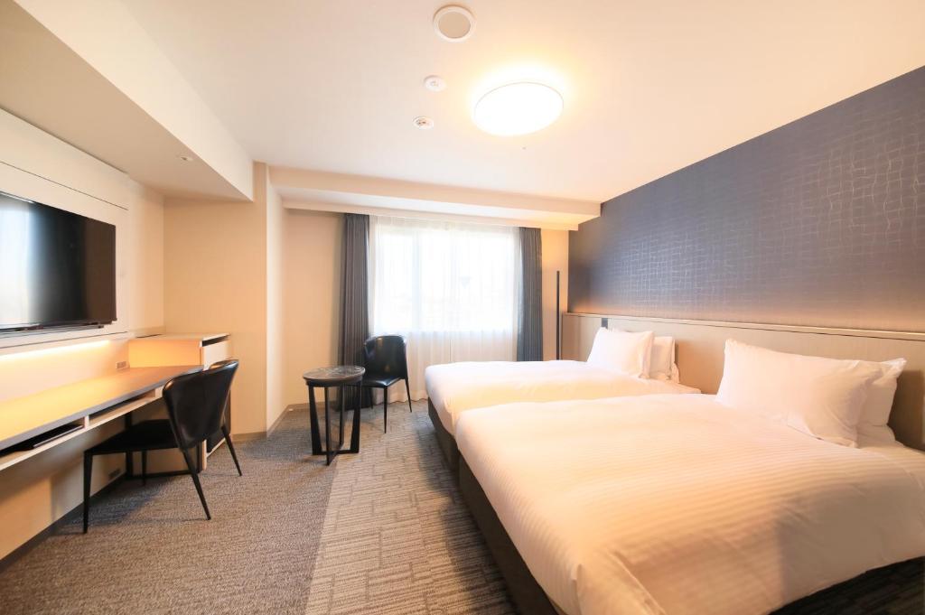 a hotel room with two beds and a desk at Richmond Hotel Yokohama Ekimae in Yokohama