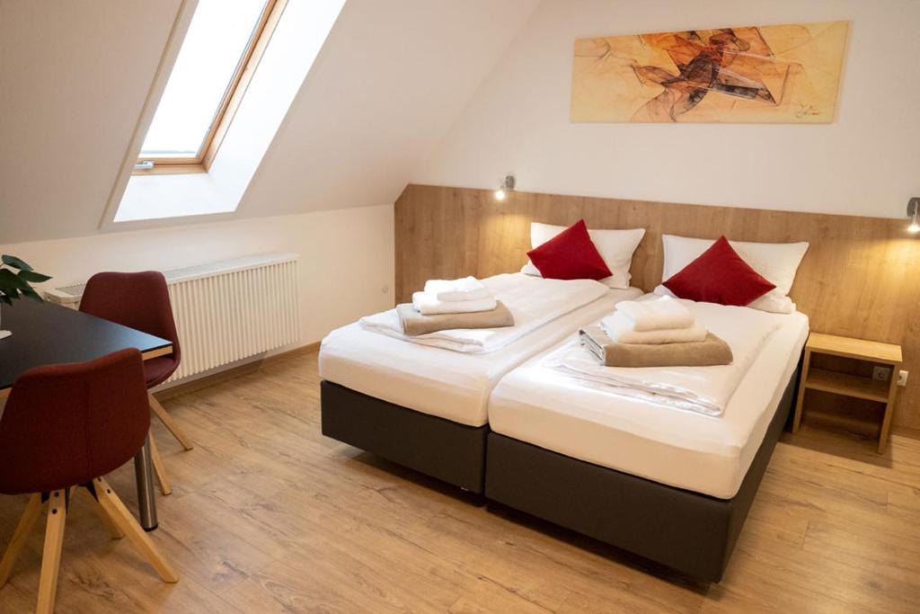 a bedroom with a bed with red pillows and a table at Lebererhof Apartments in Roßtal