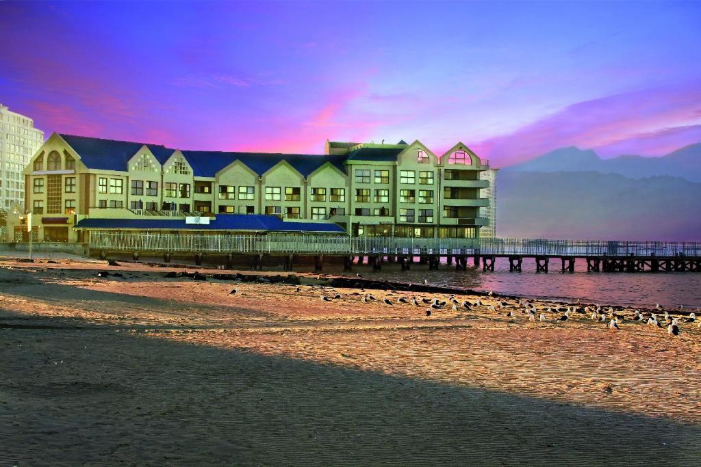 un edificio en la playa con un muelle y aves en Strand Pavilion en Strand