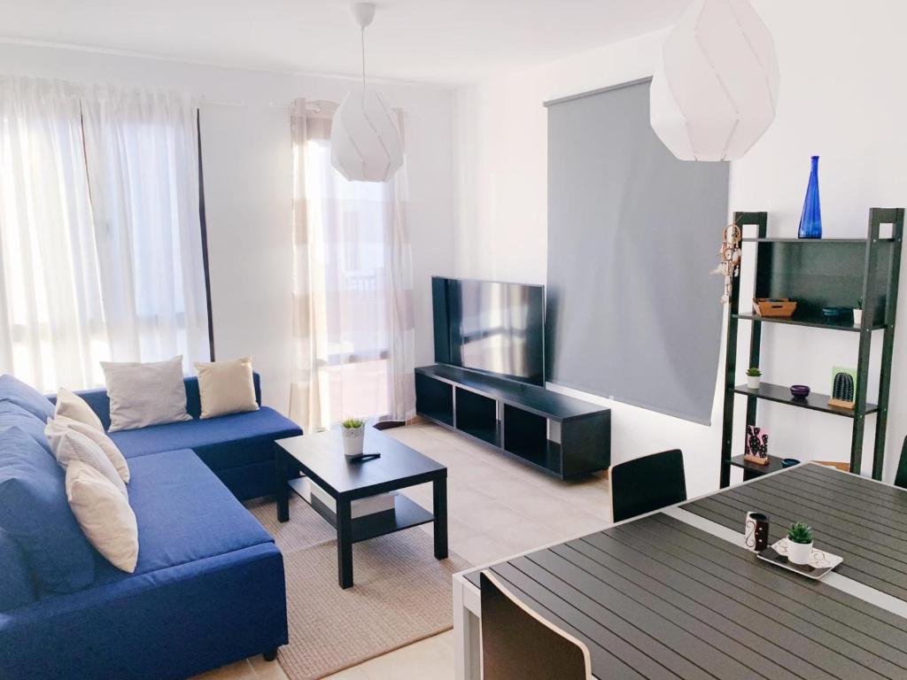 sala de estar con sofá azul y mesa en Luxury Villa Lanzarote en Playa Blanca