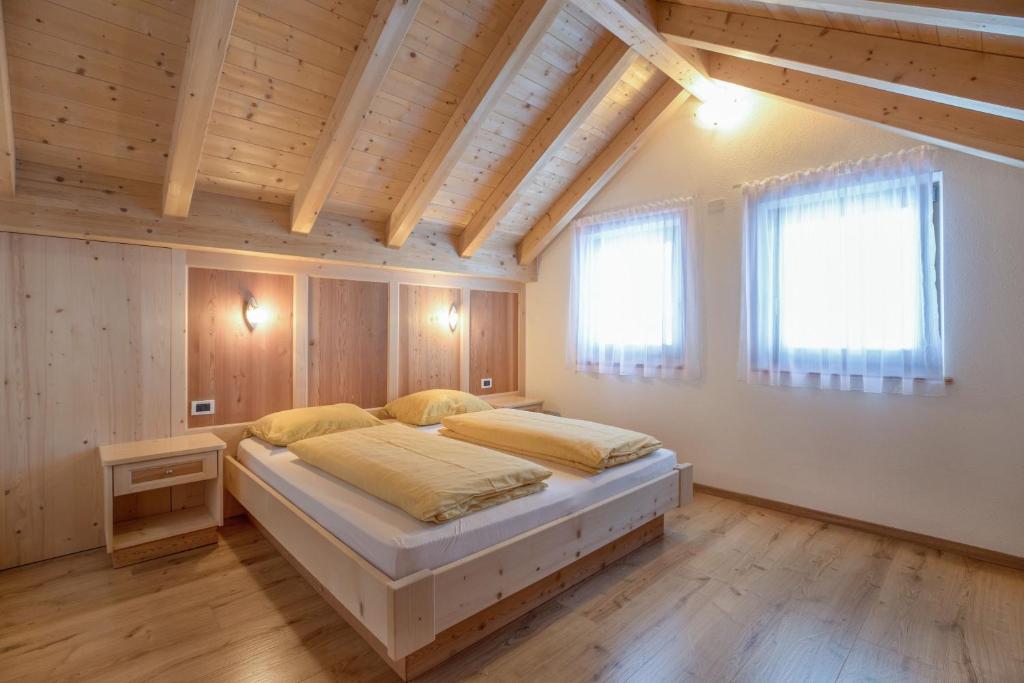 sypialnia z łóżkiem w pokoju z drewnianym sufitem w obiekcie Apartment Dolomiten w mieście San Martino in Badia