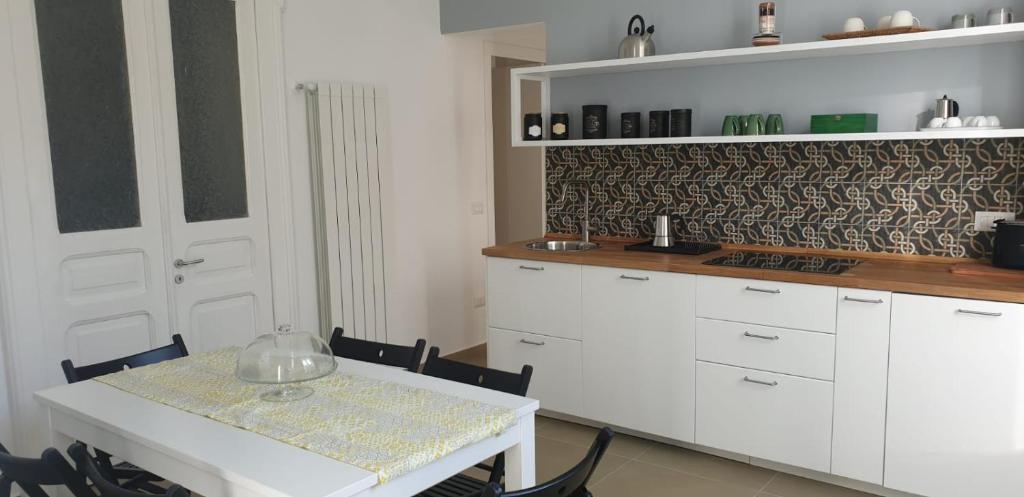 una cocina con armarios blancos y una mesa con sillas. en MaGà Station, en Nápoles