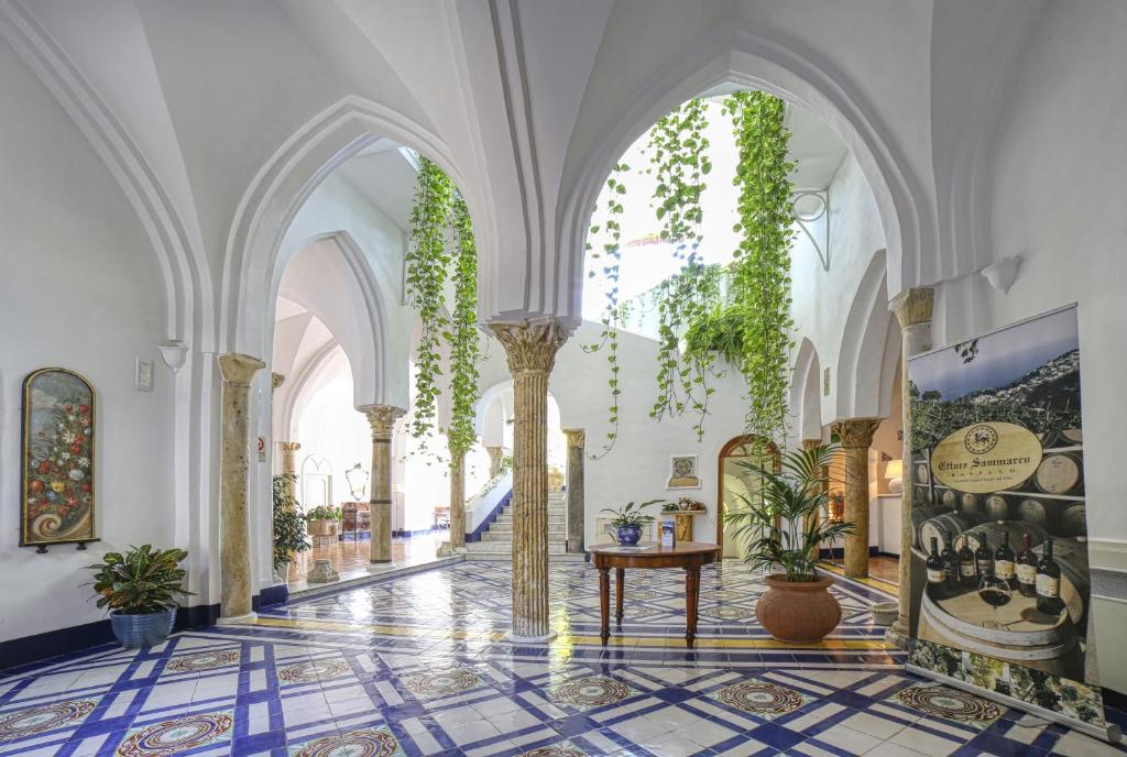 a hallway with arches and plants in a building at Palazzo Confalone in Ravello