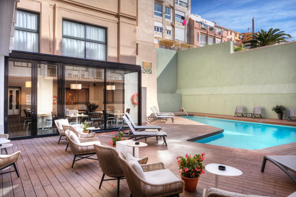 an outdoor patio with chairs and a swimming pool at Apartaments Lauria in Tarragona