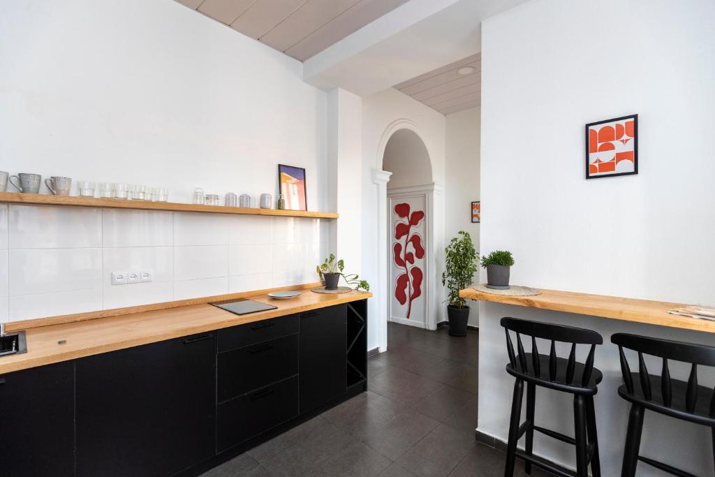 eine Küche mit schwarzen Schränken und einer Theke mit Stühlen in der Unterkunft ❂Light and Luxurious 2BR Home + Balcony in the City Center❂ in Tbilisi City