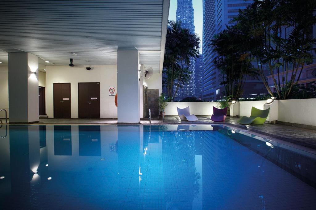 a large swimming pool in a building with tall buildings at Crown Regency Serviced Suites in Kuala Lumpur