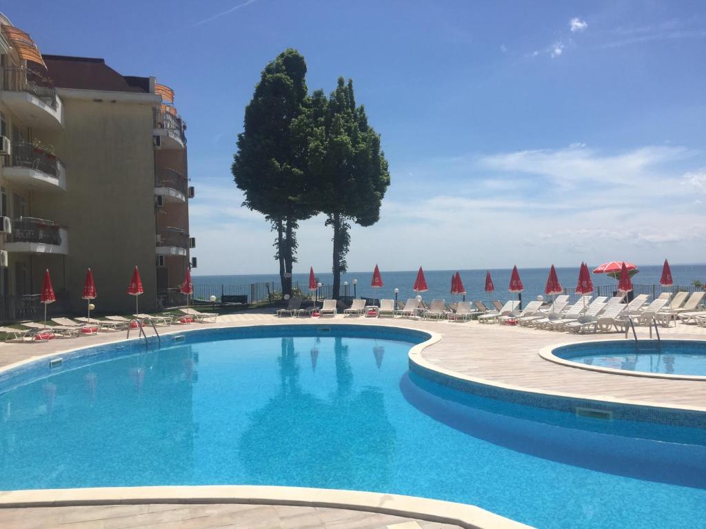 a large swimming pool with chairs and umbrellas at Helios Hotel in Balchik