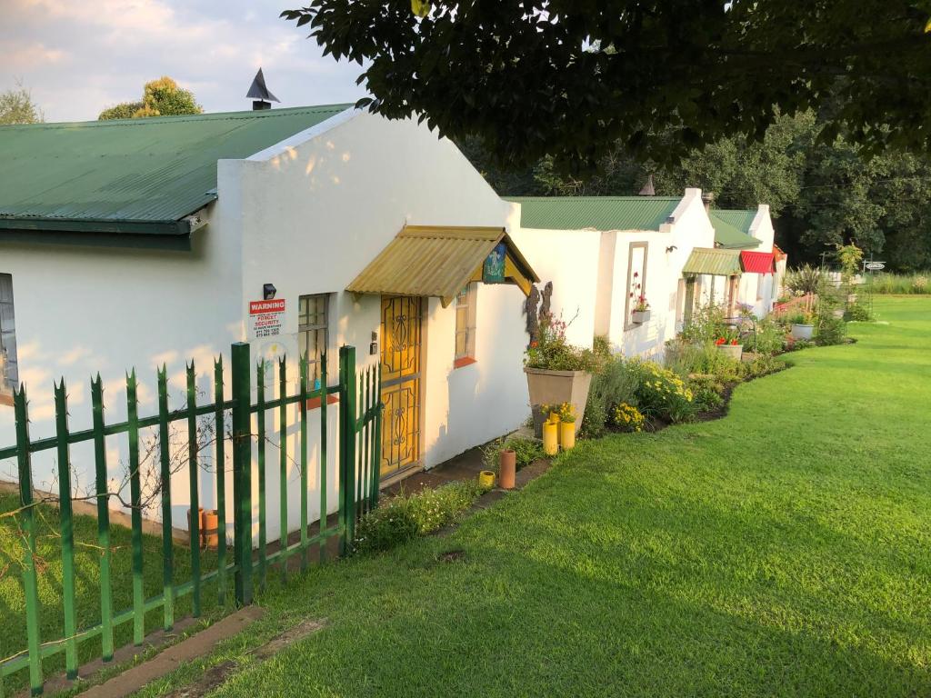a white house with a fence and a yard at Peace Corner Cottages in Dullstroom