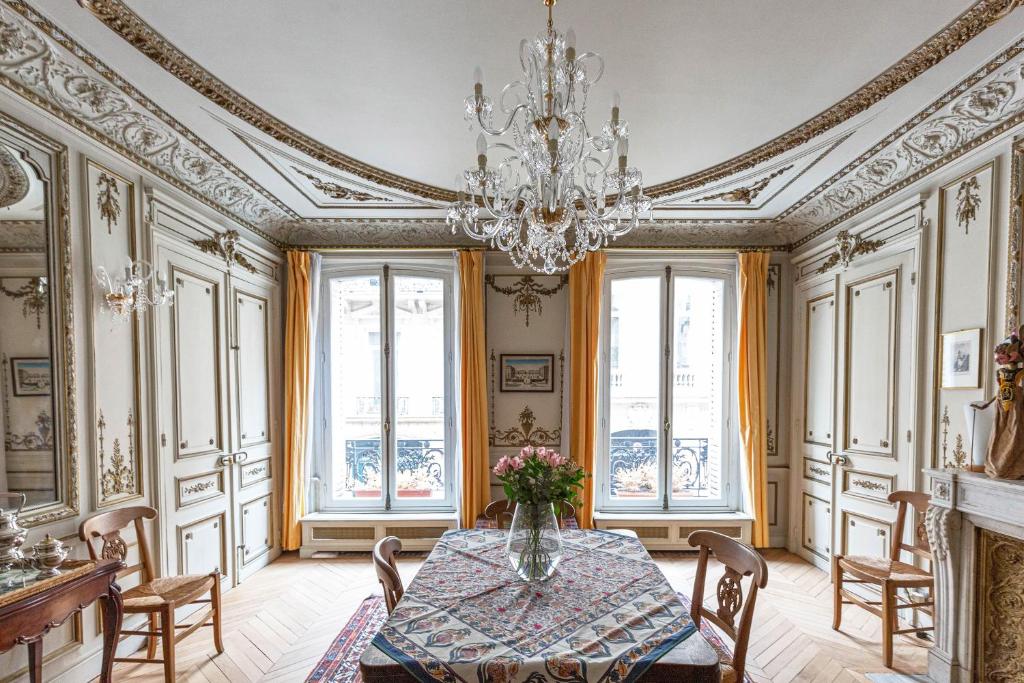 a dining room with a table and a chandelier at Veeve - Classical Features in the 9th in Paris