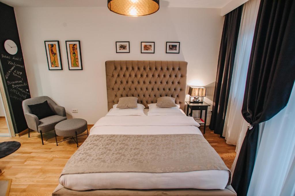 Apartments Doclea في بودغوريتسا: غرفة نوم بسرير كبير وكرسي